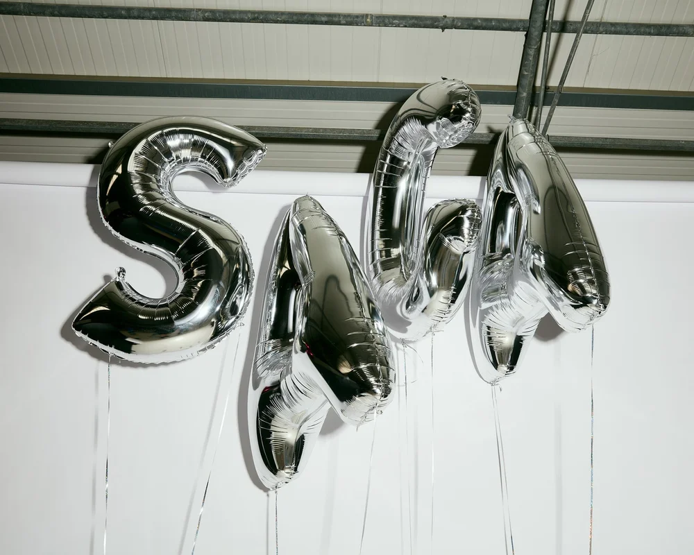 Chrome SAGA letter balloons floating against the studio ceiling