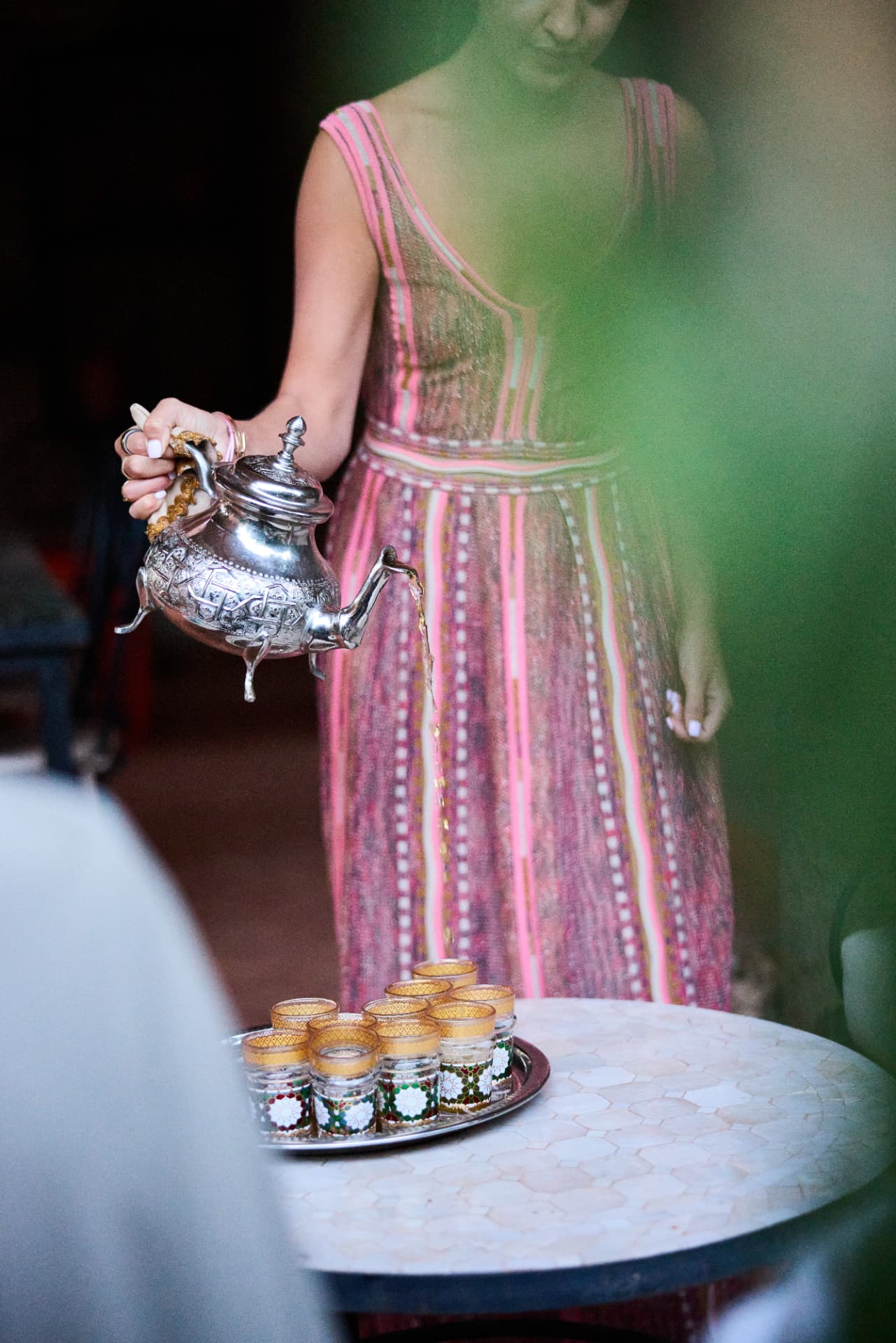 Woman in a pink kaftan pouring mint tea