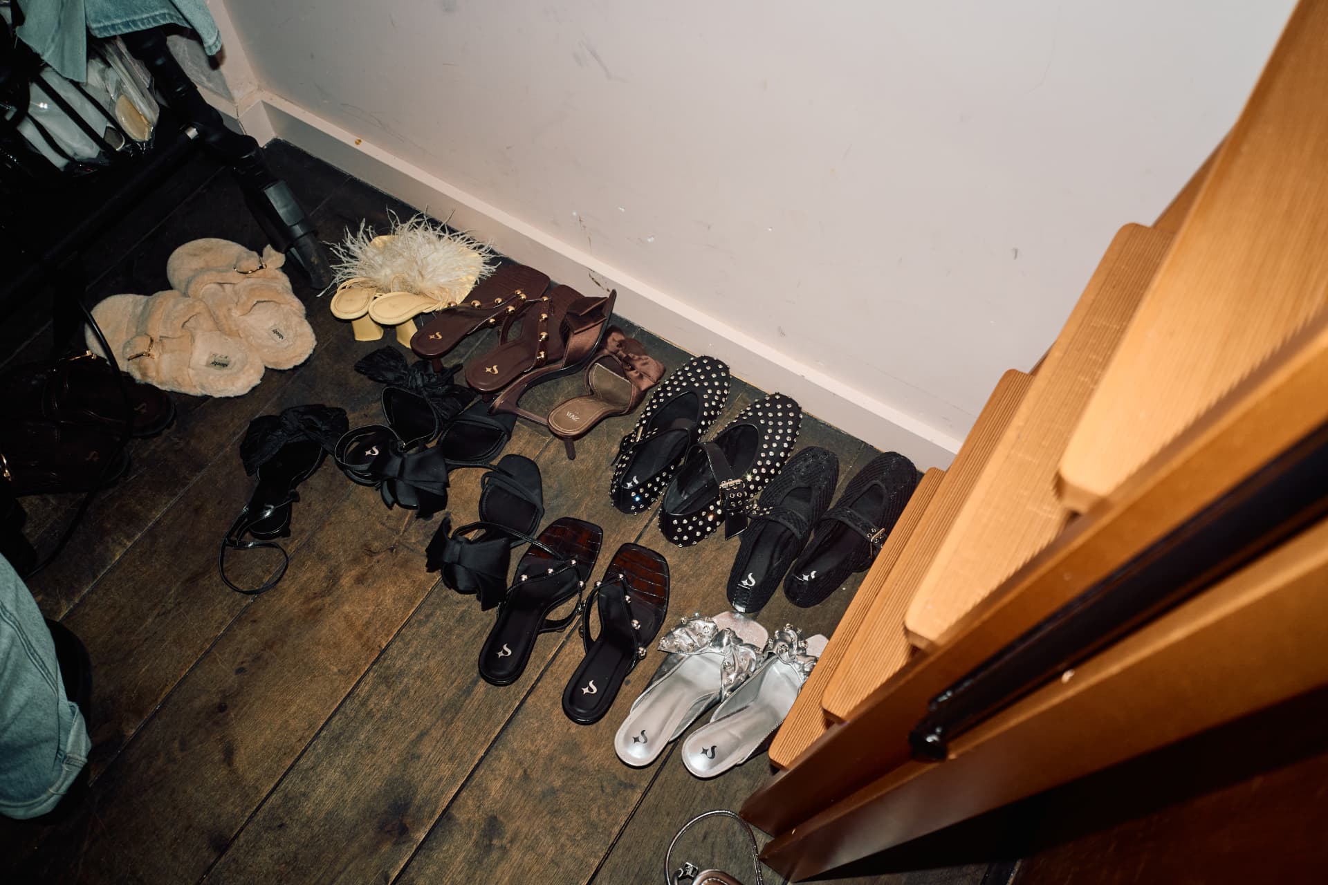 Shoes lined up on a dark wooden floor by the stairs