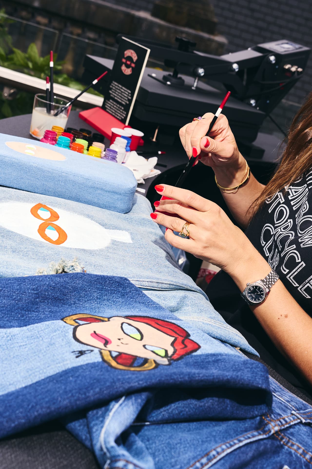 Artist hand-painting a character onto a denim jacket