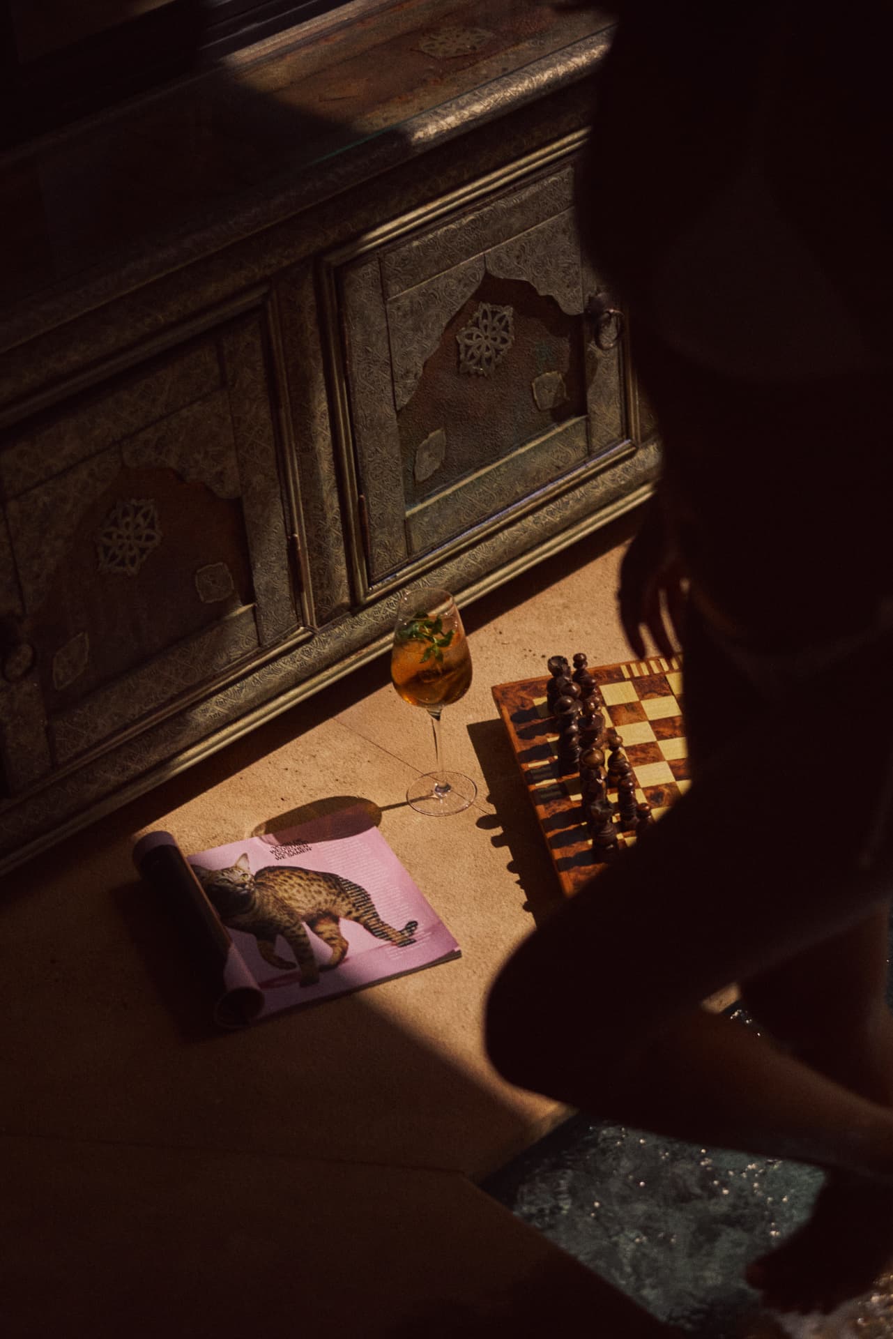 Chess board, drink and painted cushion in a shaded corner