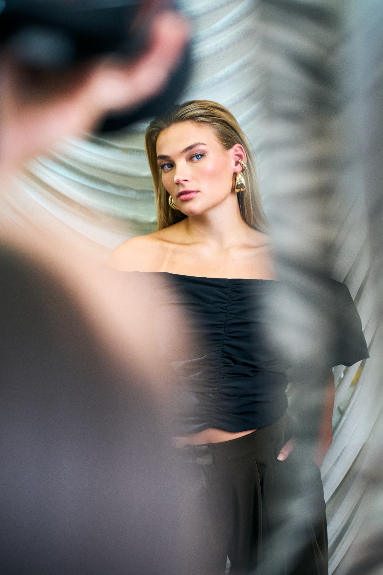 Model in a black off shoulder top shot past a camera