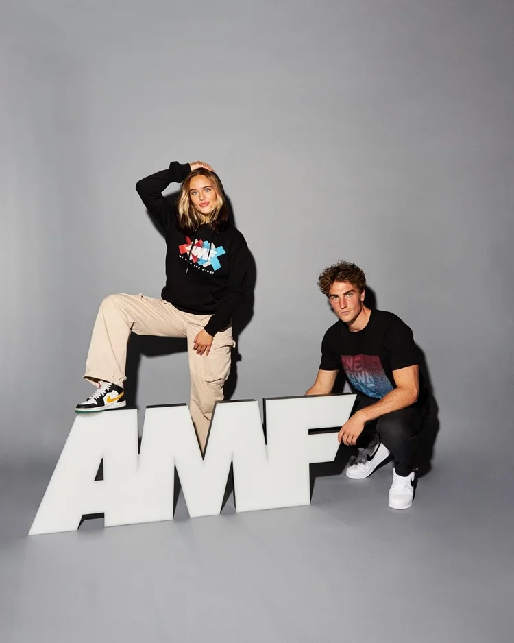 Two models posed on oversized AMF letters in a studio