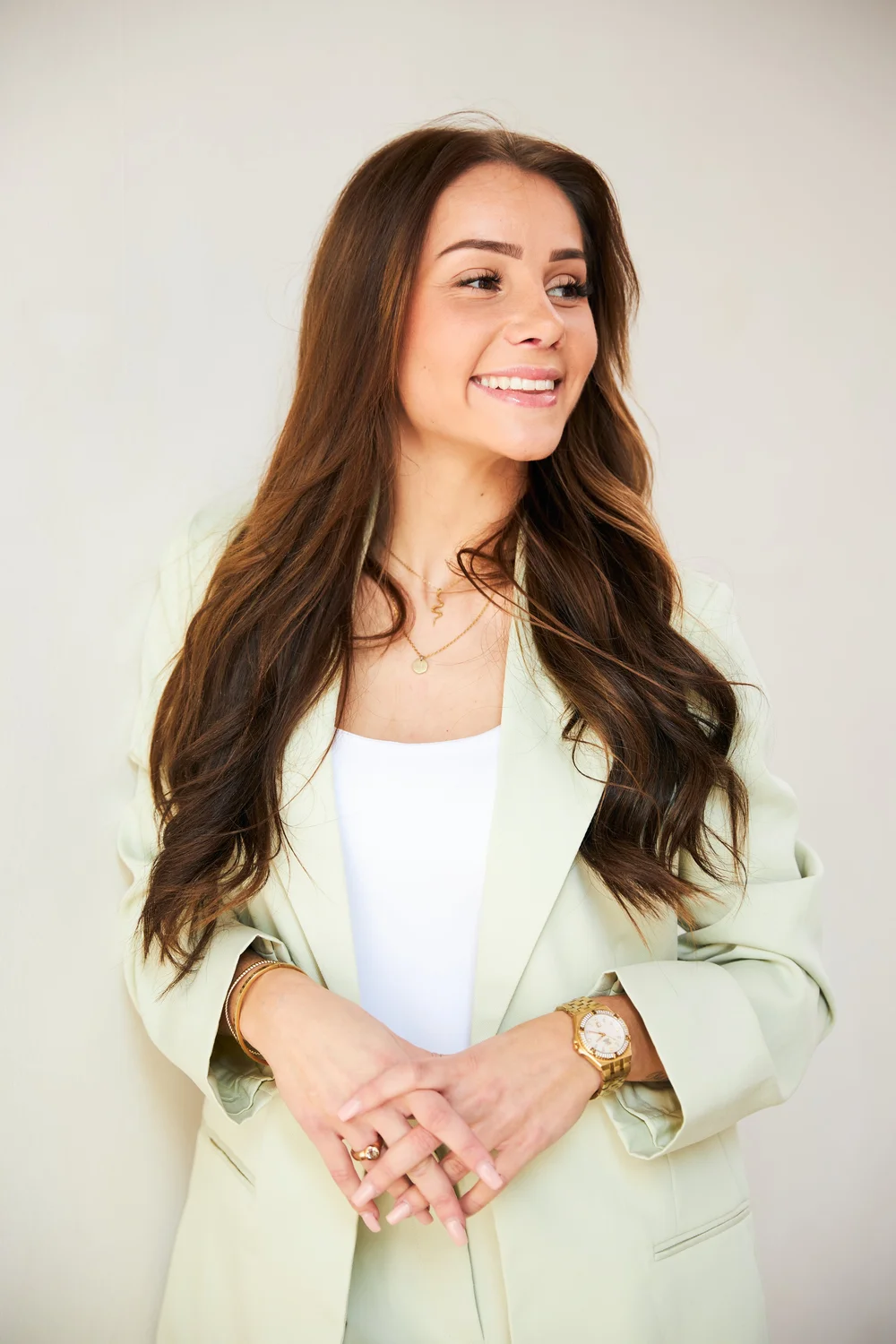 Woman in a sage blazer laughing off camera