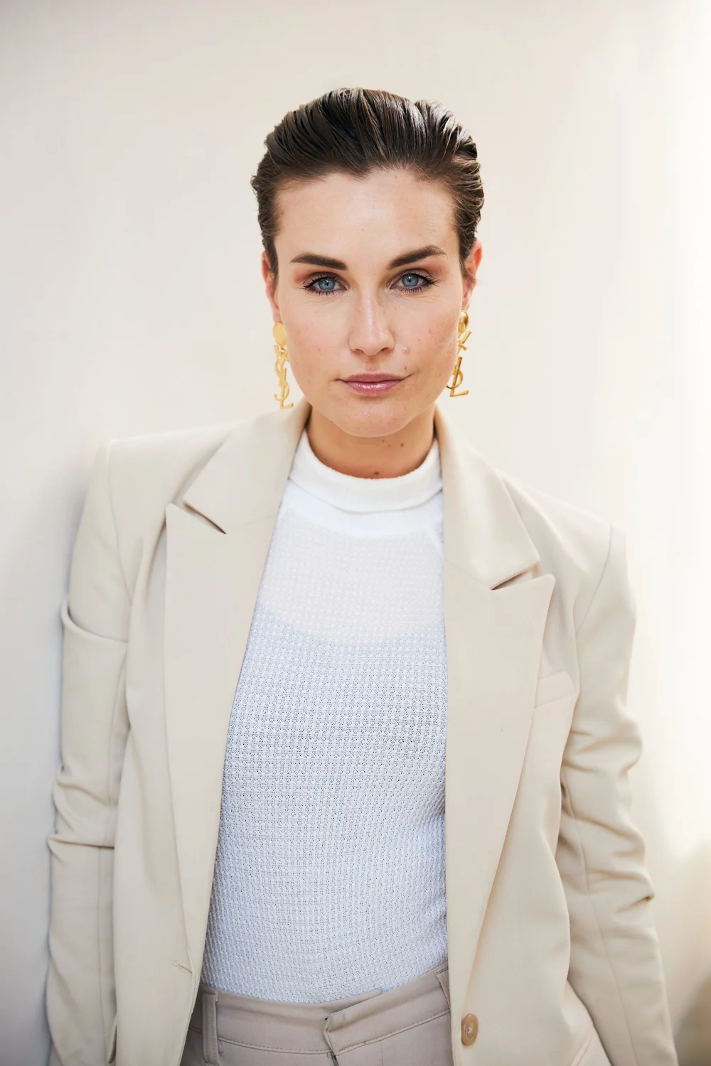 Portrait of a woman in a bone blazer with gold earrings