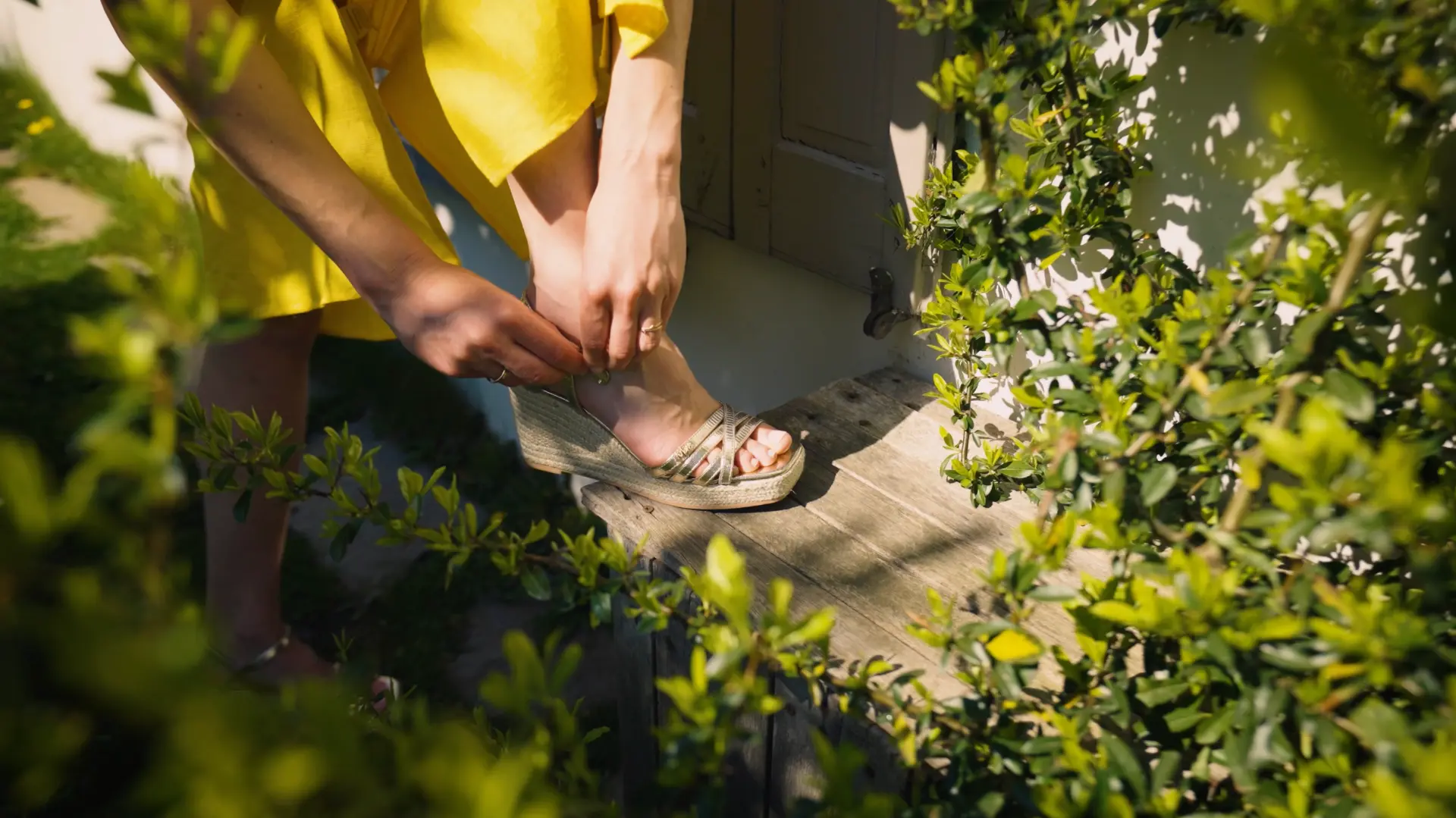 Close-up of a woman fastening a wedge sandal in the sun