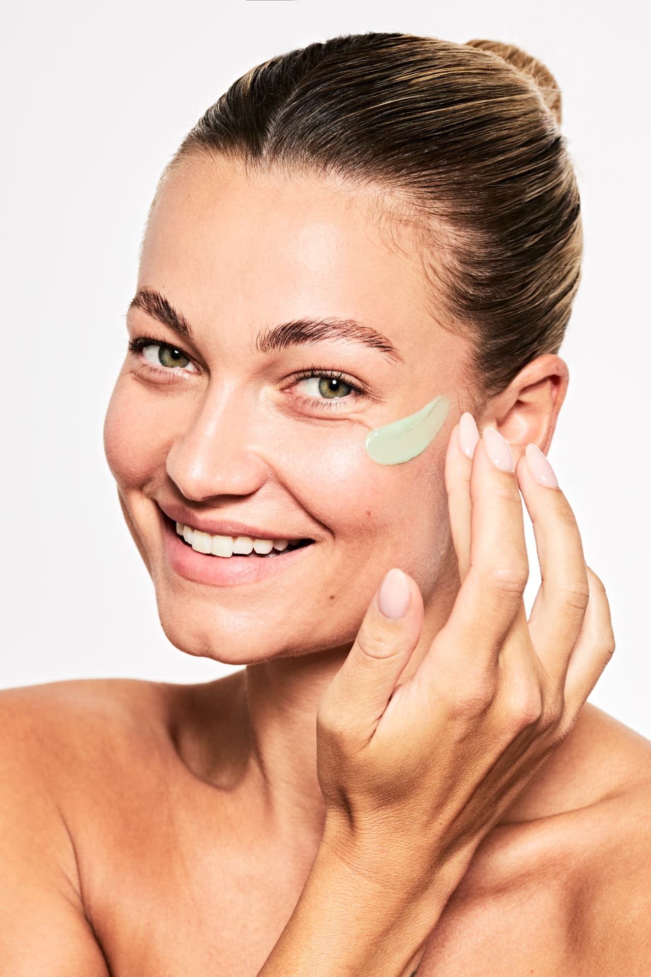Model applying a stroke of cream under the eye