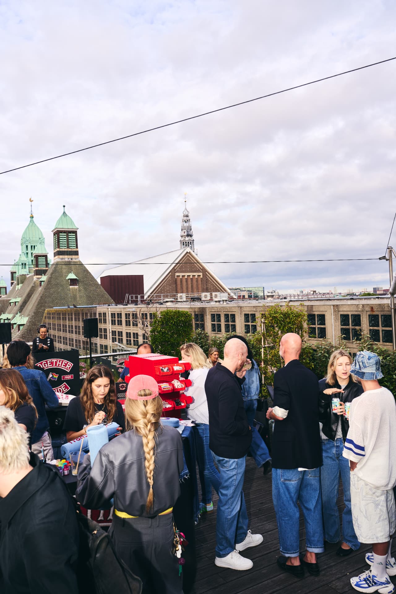 Rooftop crowd around the pin station with the Amsterdam skyline behind