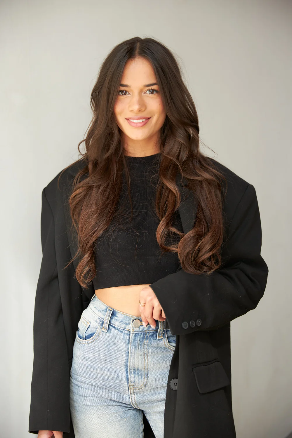 Woman in a black blazer and denim smiling at camera