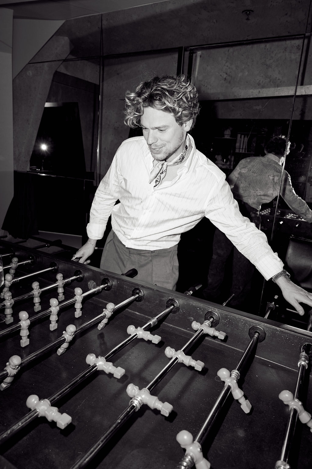 Guest playing foosball late in the night, black and white